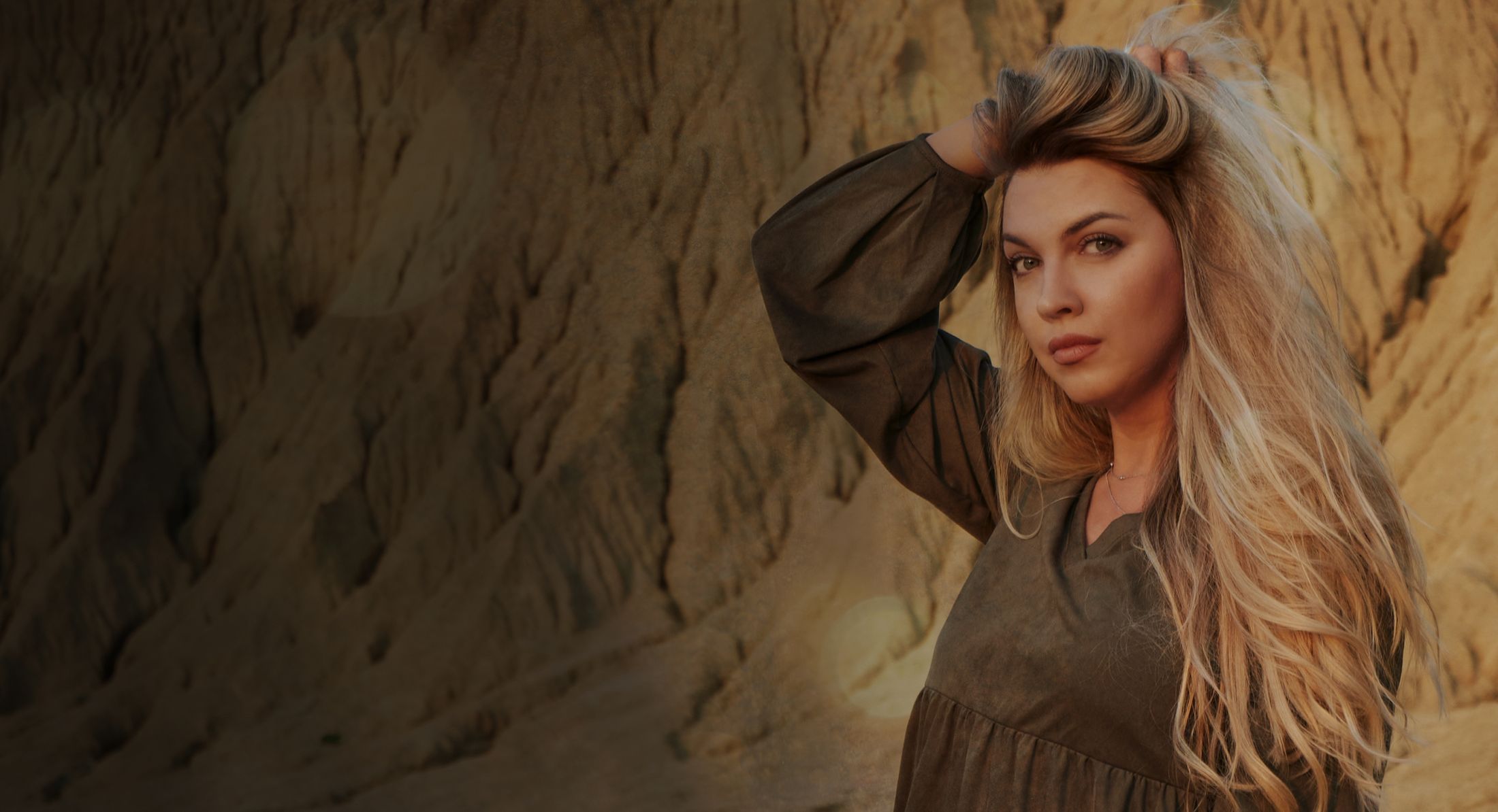 Woman posing against a textured sandy background.