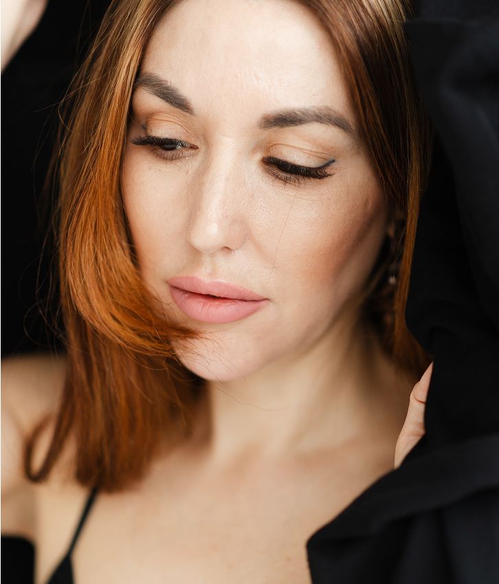 Woman with red hair and soft makeup.