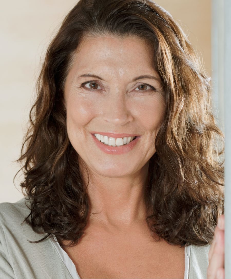 Smiling woman with long, wavy hair indoors.